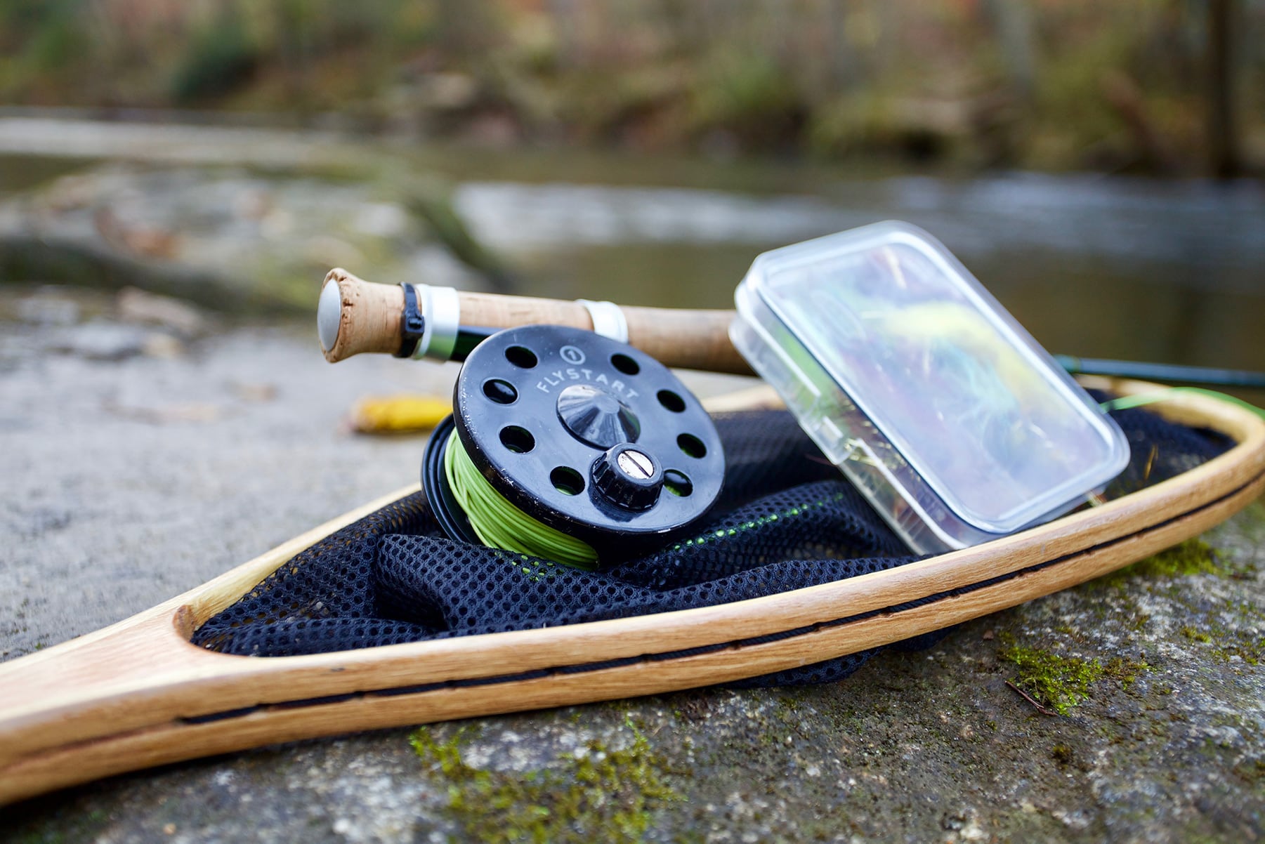 Flyfishing gear neatly stacked on a boulder next to a stream