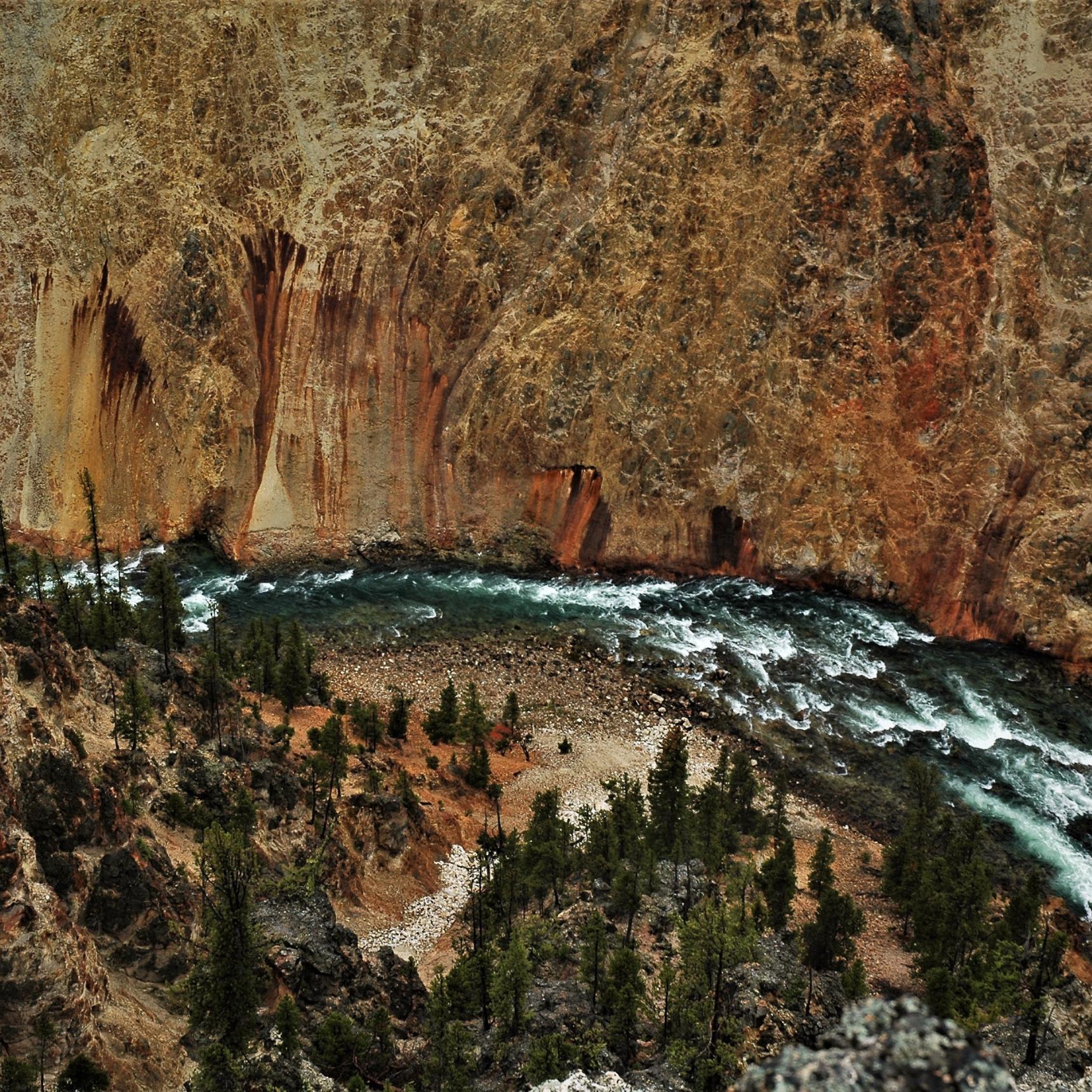 Aerial view of a whitewater river with a slight curve to the left at the bottom of a deep, steep canyon